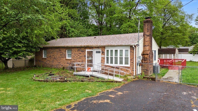 view of front of home featuring brick siding, a gate, a chimney, and roof with shingles