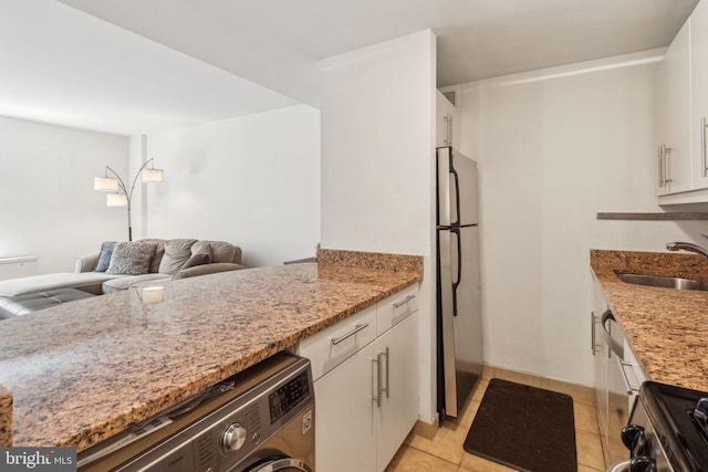 219 S 18th St Unit 1422, Philadelphia, PA 19103 - kitchen featuring light tile patterned floors, a sink, appliances with stainless steel finishes, light stone countertops, and washer / dryer