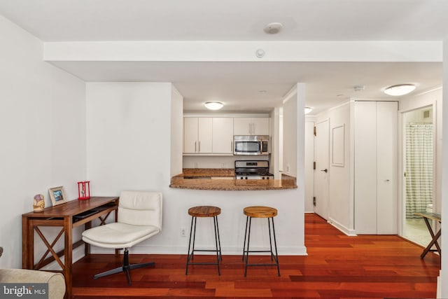 219 S 18th St Unit 1422, Philadelphia, PA 19103 - kitchen featuring appliances with stainless steel finishes, wood finished floors, a breakfast bar area, and white cabinets