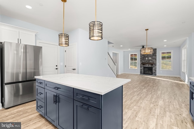 W Main Blvd, Lutherville Timonium, MD 21093 - kitchen with decorative light fixtures, a large fireplace, white cabinets, freestanding refrigerator, and light wood finished floors