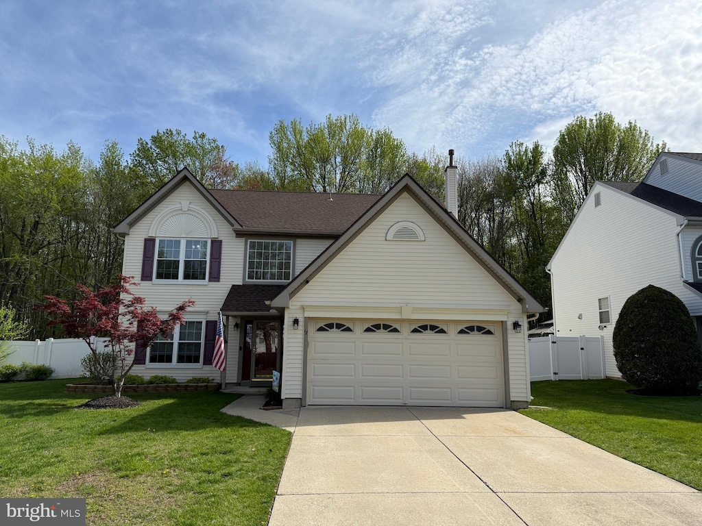 traditional home with a front lawn, a gate, a chimney, concrete driveway, and fence