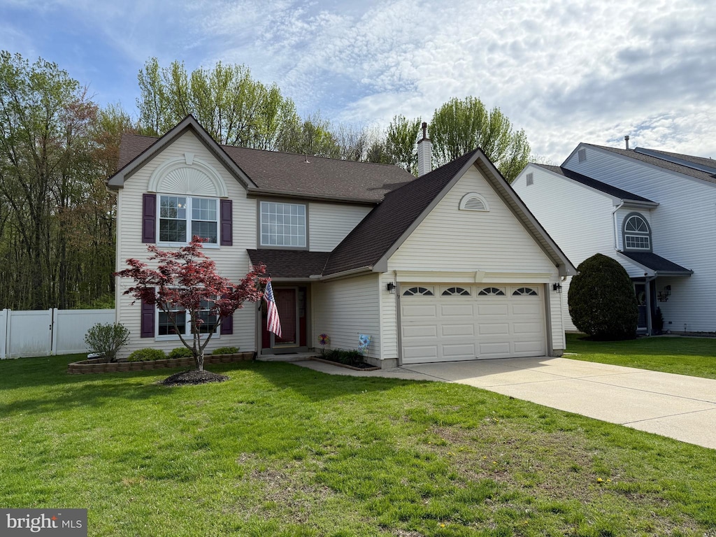 traditional home featuring a front lawn, driveway, a chimney, an attached garage, and fence