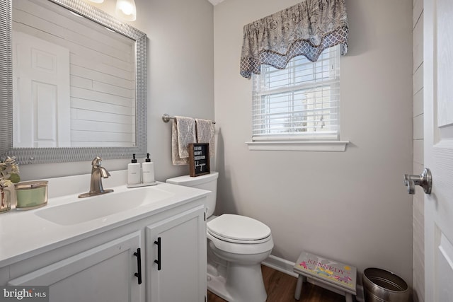 bathroom featuring vanity, baseboards, wood finished floors, and toilet