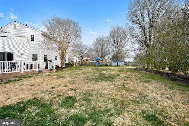 view of yard with fence, a storage shed, and a deck
