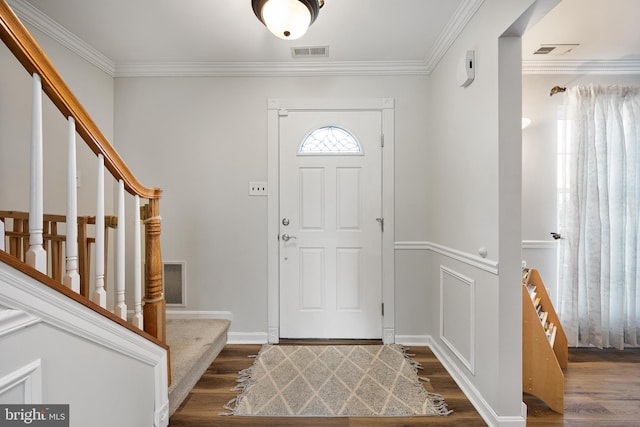foyer featuring crown molding, stairs, wood finished floors, and visible vents