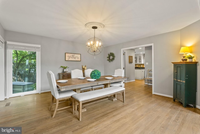 dining space with baseboards, visible vents, an inviting chandelier, and light wood-style floors