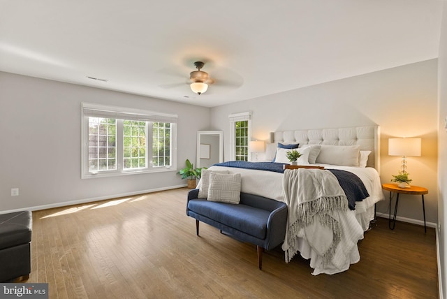 bedroom featuring a ceiling fan, baseboards, visible vents, and wood finished floors