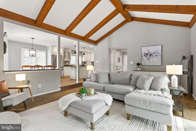 living room with beam ceiling, baseboards, wood finished floors, and high vaulted ceiling