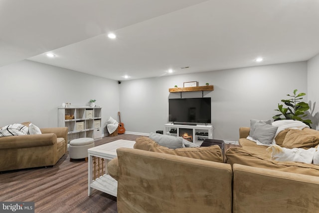 living area featuring recessed lighting, a warm lit fireplace, and wood finished floors