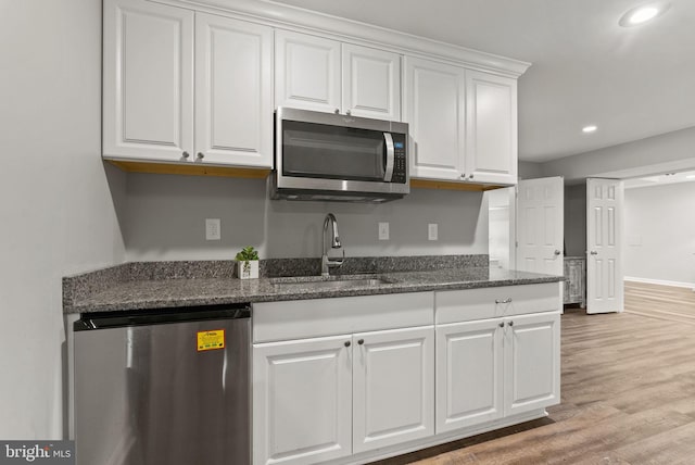 kitchen with refrigerator, recessed lighting, white cabinetry, stainless steel microwave, and a sink
