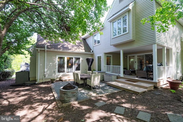 back of house featuring a shingled roof, a fire pit, and a patio area