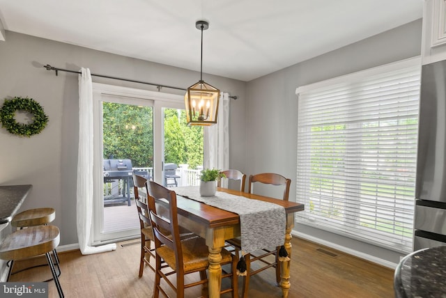 dining space featuring baseboards, a chandelier, visible vents, and light wood-type flooring