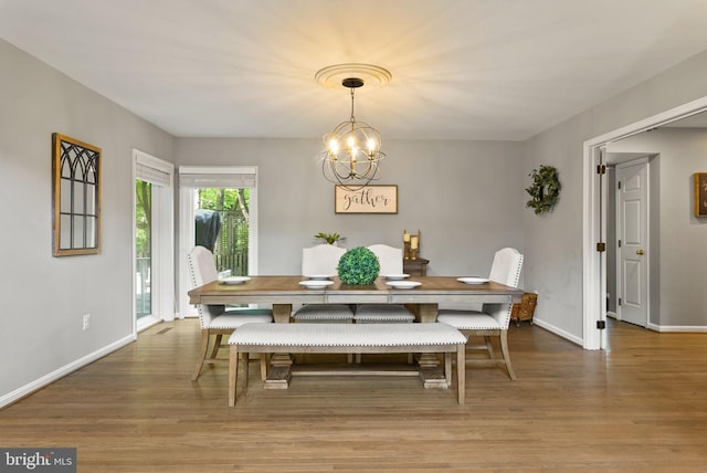 dining area featuring baseboards, wood finished floors, and a chandelier