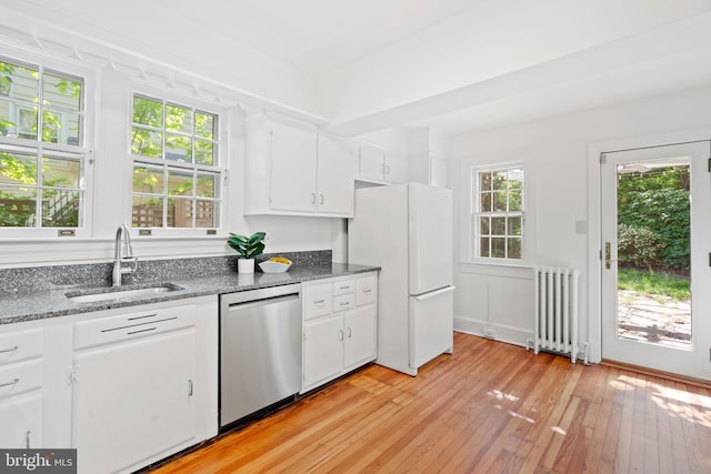 kitchen with freestanding refrigerator, radiator heating unit, white cabinetry, a sink, and dishwasher