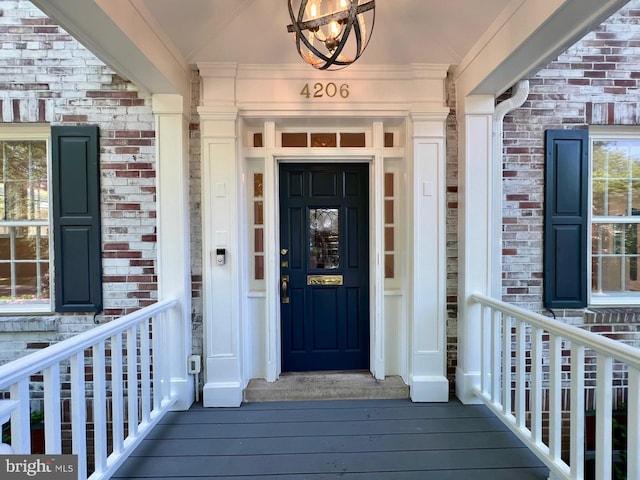view of exterior entry featuring brick siding and covered porch