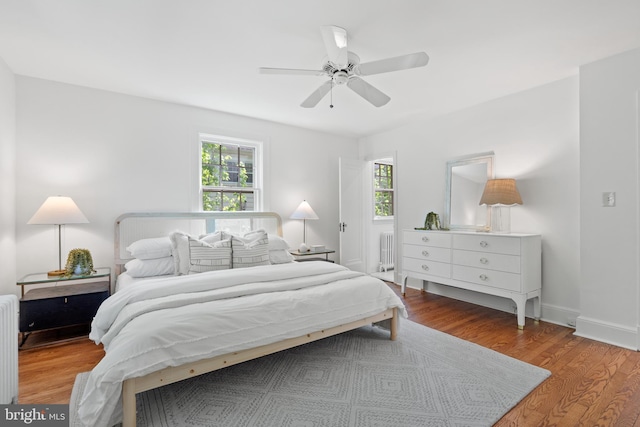 bedroom featuring a ceiling fan, wood finished floors, and radiator heating unit