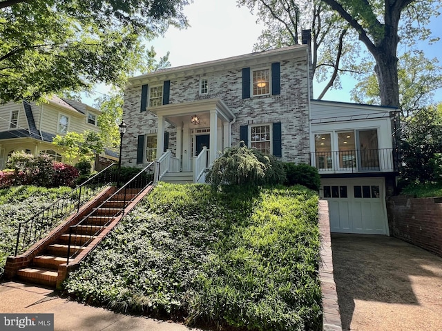 colonial inspired home with an attached garage, stairs, and driveway