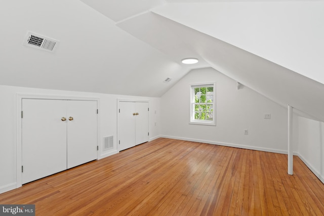 bonus room with baseboards, visible vents, light wood-style flooring, and lofted ceiling