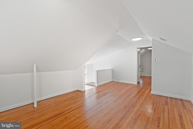 additional living space featuring baseboards, visible vents, light wood-type flooring, and lofted ceiling