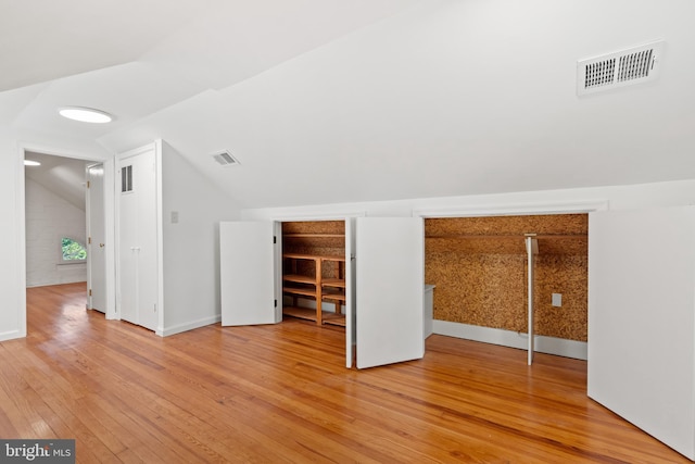 additional living space with visible vents, baseboards, light wood-style floors, and lofted ceiling