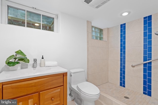 full bath with visible vents, a tile shower, toilet, and vanity