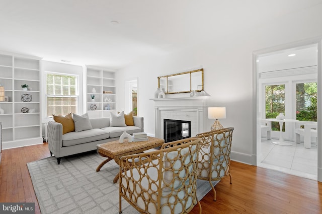 living room featuring a fireplace, built in features, plenty of natural light, and wood-type flooring