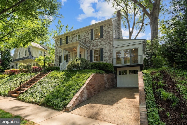 colonial-style house with concrete driveway, an attached garage, and stairway