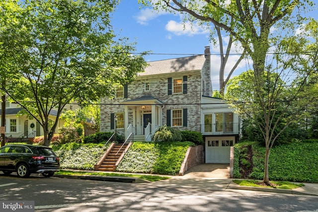 colonial house featuring driveway, a chimney, french doors, a garage, and stone siding
