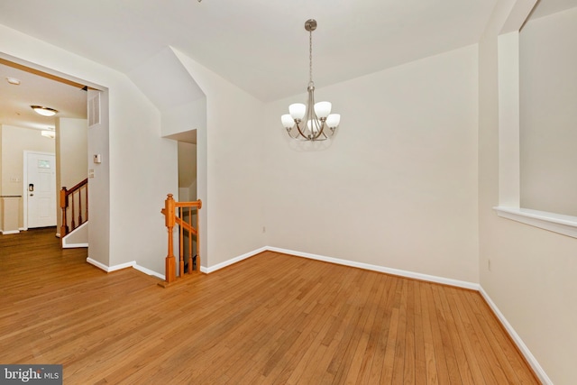 unfurnished room featuring baseboards, hardwood / wood-style flooring, and a chandelier