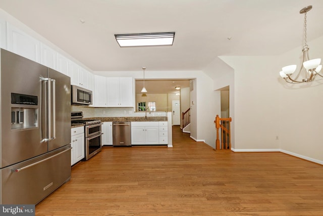 kitchen with stainless steel appliances, a chandelier, white cabinetry, light wood-style flooring, and hanging light fixtures