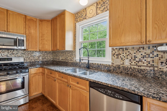 kitchen with a sink, dark stone counters, decorative backsplash, and stainless steel appliances
