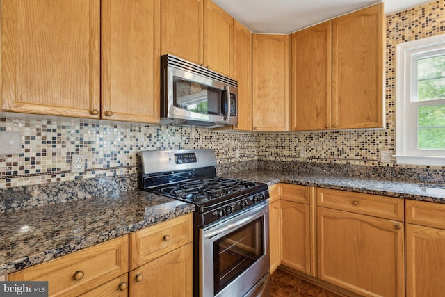 kitchen with appliances with stainless steel finishes, tasteful backsplash, and dark stone countertops