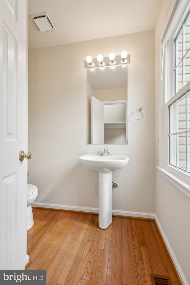 bathroom featuring toilet, baseboards, visible vents, and wood finished floors