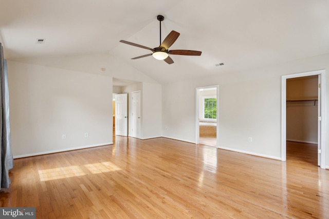 empty room featuring a ceiling fan, vaulted ceiling, light wood-style flooring, and visible vents