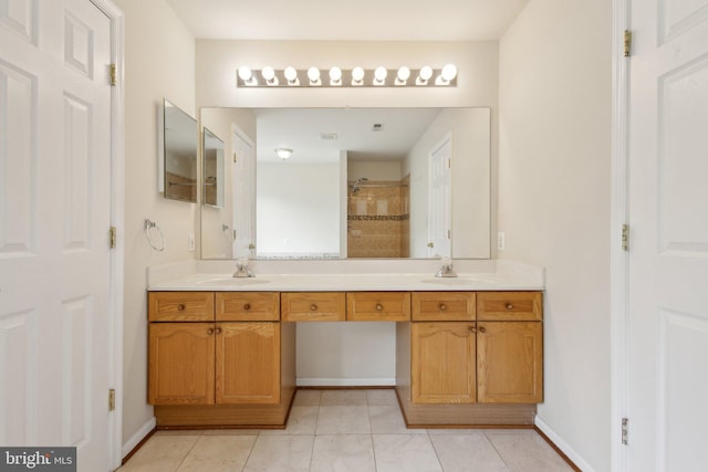 bathroom with double vanity, a sink, baseboards, and tiled shower