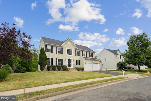 colonial house featuring an attached garage, driveway, and a front yard