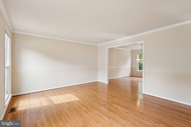 spare room featuring baseboards, ornamental molding, light wood-style flooring, and visible vents