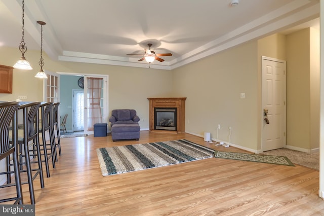 2038 E Harrisburg Pike, Middletown, PA 17057 - living room with a tray ceiling, light wood-type flooring, baseboards, ceiling fan, and a glass covered fireplace