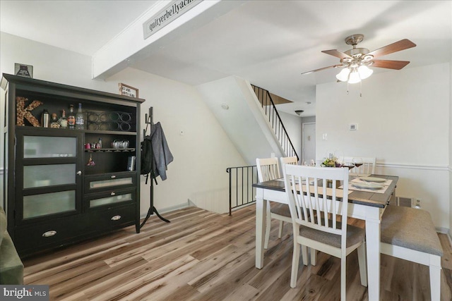 dining space with ceiling fan, wood finished floors, and stairway