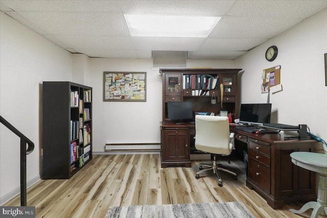 office space featuring baseboards, a baseboard radiator, light wood-style flooring, and a drop ceiling