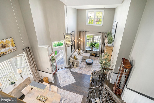 living area with baseboards, a high ceiling, and wood finished floors