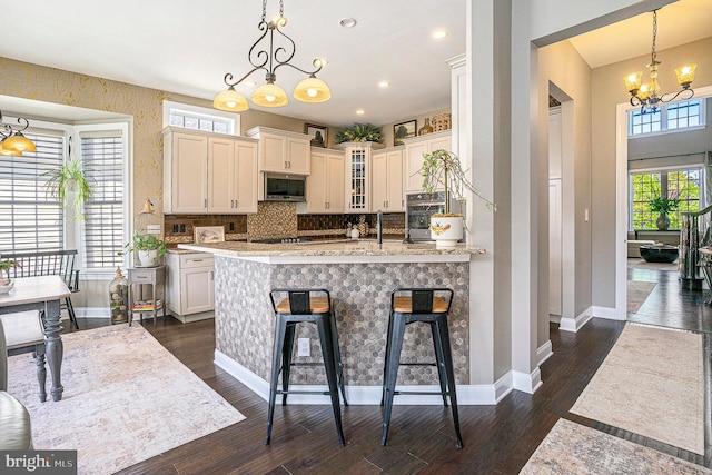 kitchen featuring stainless steel appliances, baseboards, an inviting chandelier, and dark wood-style floors