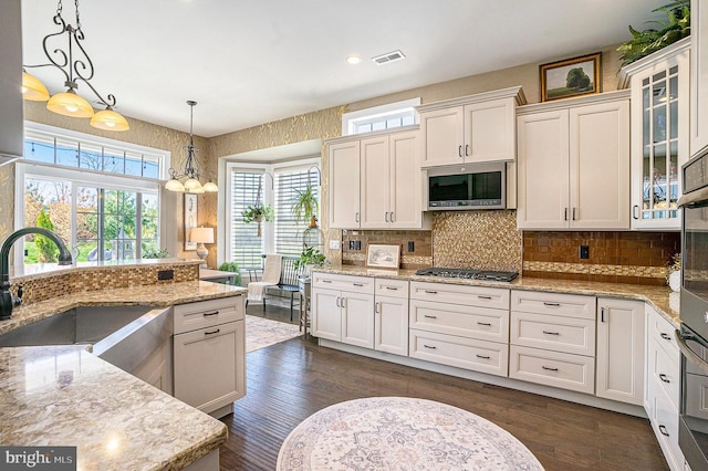 kitchen with appliances with stainless steel finishes, a healthy amount of sunlight, a sink, and visible vents