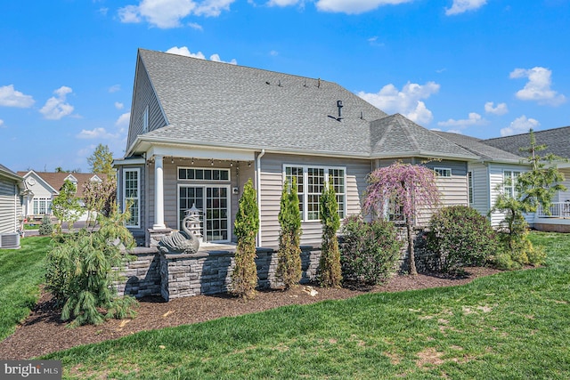 rear view of house featuring a lawn, a shingled roof, and central AC unit