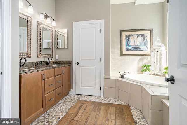 bathroom with double vanity, a sink, and a garden tub