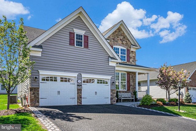 craftsman-style house featuring a garage, aphalt driveway, and stone siding