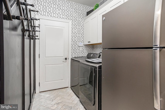 clothes washing area featuring brick floor, wallpapered walls, cabinet space, and washing machine and clothes dryer