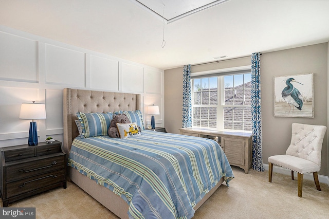 bedroom featuring a decorative wall, visible vents, attic access, and light colored carpet