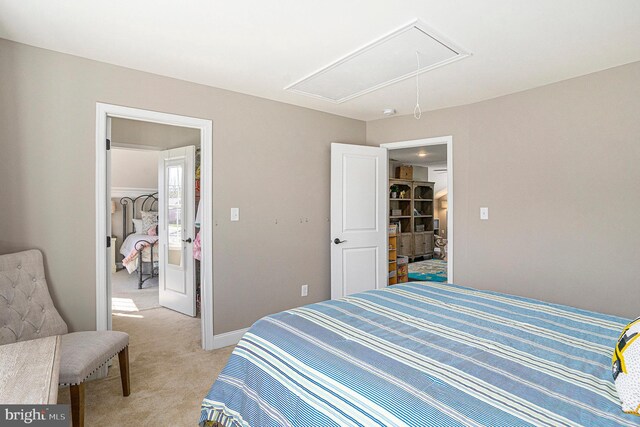 bedroom featuring baseboards, attic access, and light colored carpet
