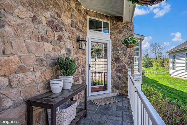 property entrance with a yard and stone siding